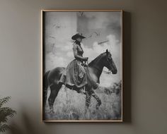 a black and white photo of a woman on a horse in a field with grass