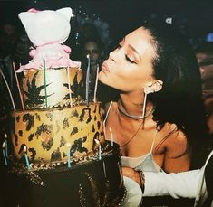 a woman blowing out candles on a large multi - tiered cake with leopard print