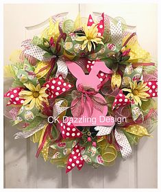 the wreath is decorated with pink, yellow and green flowers on it's front door