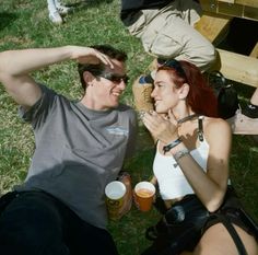 two people sitting on the grass next to each other with beer in their hands and one person wearing sunglasses