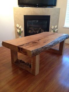 a wooden table sitting on top of a hard wood floor next to a fire place