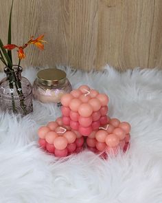 three vases with flowers in them sitting on a white fur covered floor next to some candles