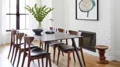 a dining room table with six chairs and a potted plant in the center on top