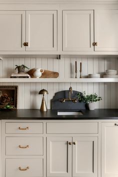 a kitchen with white cupboards and black counter tops, gold handles and brass pulls