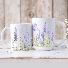 two coffee mugs with painted flowers and butterflies on them, sitting next to each other