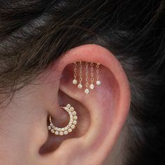 a woman wearing gold ear piercings with pearls