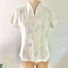 Very Classic And Sophisticated Asian Chinese Style Blouse Top W/ Mandarin Collar And Rope Button Closures. Pretty Ivory Floral Pattern With Subtle Silver Shine 100% Polyester, Unlined Very Slight Shoulder Pads (Removable) Size:Xl Tagged But Seems More Like M To L Modern Day Measurements. B:19.5” W:17” L:23” Spring Wedding Button-up Blouse, White Fitted Blouse With Back Button Closure, Elegant Short Sleeve Top With Buttons, Classic Summer Blouse With Covered Buttons, White Fitted Blouse With Covered Buttons, Fitted White Blouse With Covered Buttons, Fitted White Tops With Covered Buttons, Elegant Summer Tops With Back Button Closure, Fitted Summer Tops With Covered Buttons