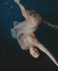 a woman floating in the water wearing a dress