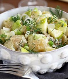 a white bowl filled with potatoes and cucumbers