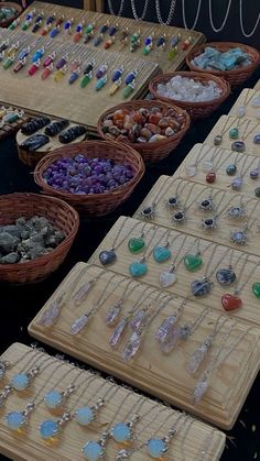 many necklaces are displayed on wooden trays with beads and stones in baskets next to each other