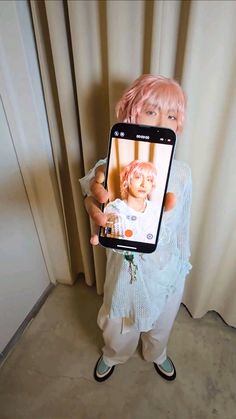 a person holding up a cell phone with a doll on it's face and an image of a child in the screen