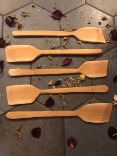 three wooden spatulas sitting on top of a tile floor next to dried flowers