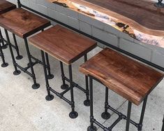 four wooden stools sitting next to each other in front of a counter with metal legs