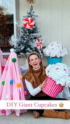 a woman sitting on the ground with cupcakes in front of her and a christmas tree behind her