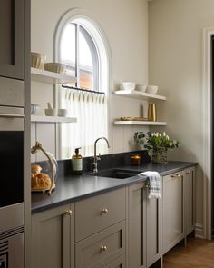 a kitchen with an arched window and black counter tops