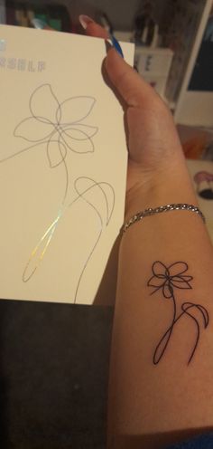 a woman's arm with a tattoo on it and a card in the background