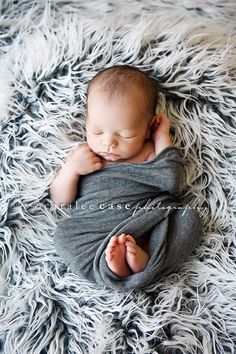 a baby wrapped in a blanket on top of a fluffy rug