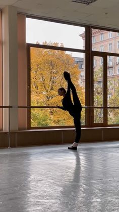 a person doing a handstand in front of a large window with trees outside