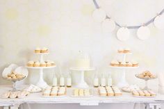 a table topped with cakes and cupcakes on top of white tablesclothes