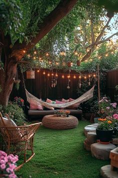 a hammock in the middle of a yard with lights strung over it and flowers on the ground