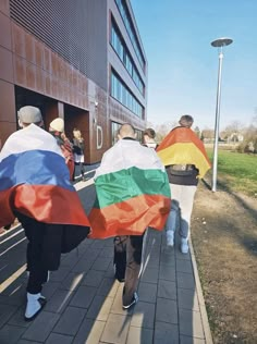 people walking down the sidewalk with flags on their backs