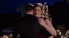 a man and woman embracing in front of christmas lights