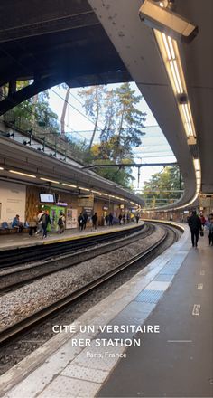 a train station with people walking on the platform and in the background, there is an overhead walkway