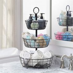 three tiered baskets filled with towels and soaps in front of a bathroom mirror