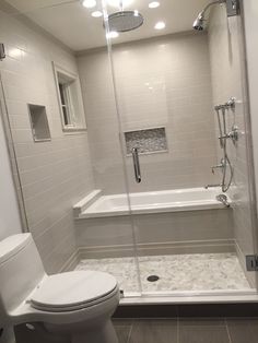 a white toilet sitting next to a bath tub in a bathroom under lights and a walk in shower