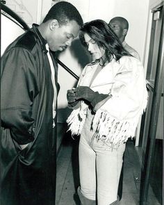 a man and woman standing next to each other in front of a door with an umbrella