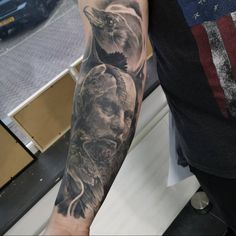 a man's arm with a black and grey tattoo design on the left sleeve