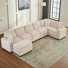 a living room with a large sectional couch and rugs in front of the window