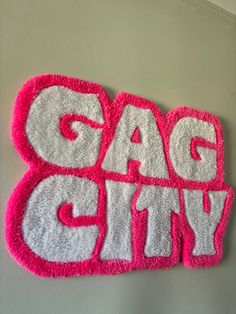 a pink and white sign that says gag city on the side of a gray wall