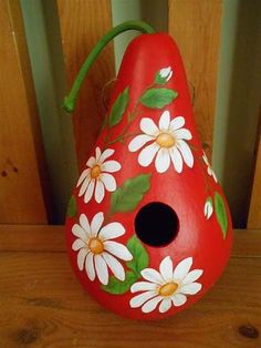 a red vase with white daisies painted on it