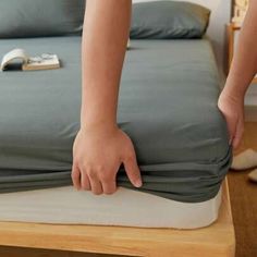 a person reaching down on a bed that has been made into a mattress with the cover pulled back