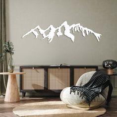 a living room with a chair, table and mountains cutout on the wall above it