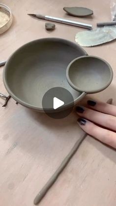 a woman is holding two spoons over a bowl