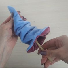 two hands are holding a toothbrush in a blue cloth wrapped around a toothpick