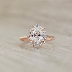 a close up view of a diamond ring on a wooden surface with the center stone surrounded by smaller diamonds