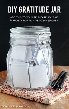 a glass jar filled with notes on top of a wooden table next to a pair of scissors