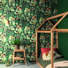 a bedroom with green wallpaper and a wooden bed in front of a plant covered wall