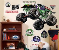 a young boy laying on the floor in front of a monster truck wall decal