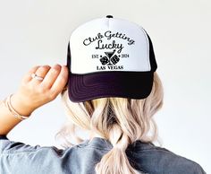 the back of a woman's head wearing a black and white trucker hat