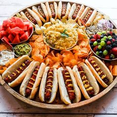 a platter filled with hot dogs, chips and fruit