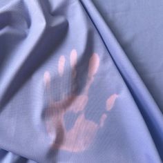 an image of a hand print on a blue sheet with pink and orange ink in it