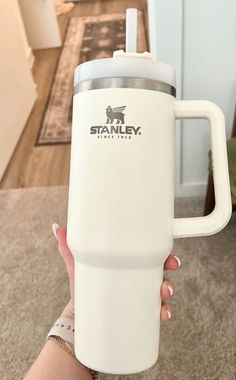 a woman holding up a white travel mug