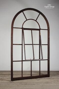 an old arched window with wooden frame on the floor in front of a white wall