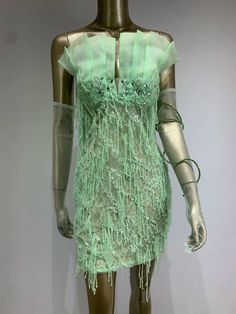 a mannequin wearing a green dress with ruffles on it's shoulders