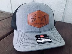 a gray and black trucker hat with a leather patch on the front sitting on a wooden table