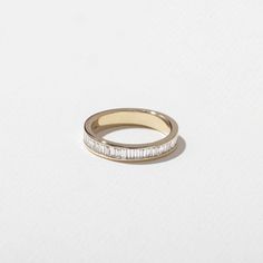 a gold ring with white stones on top and a thin band around the middle, against a white background